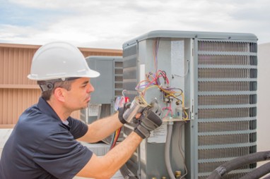 A Shamy Heating & Air Conditioning technician working on a unit. Shamy offers AC repair, maintenance, and replacement in Oregon
